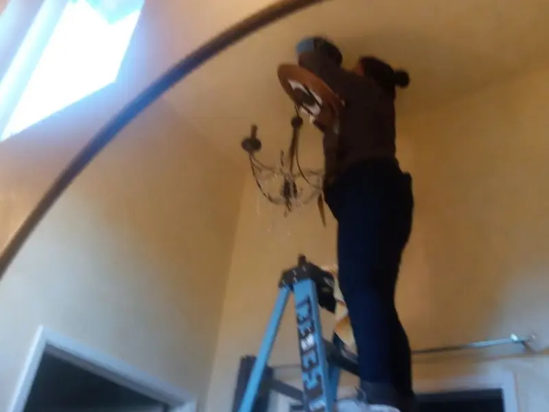 Electrician installing a chandelier in a Dent residence